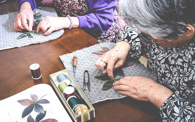 close up of seniors working on a pressed leaf craft