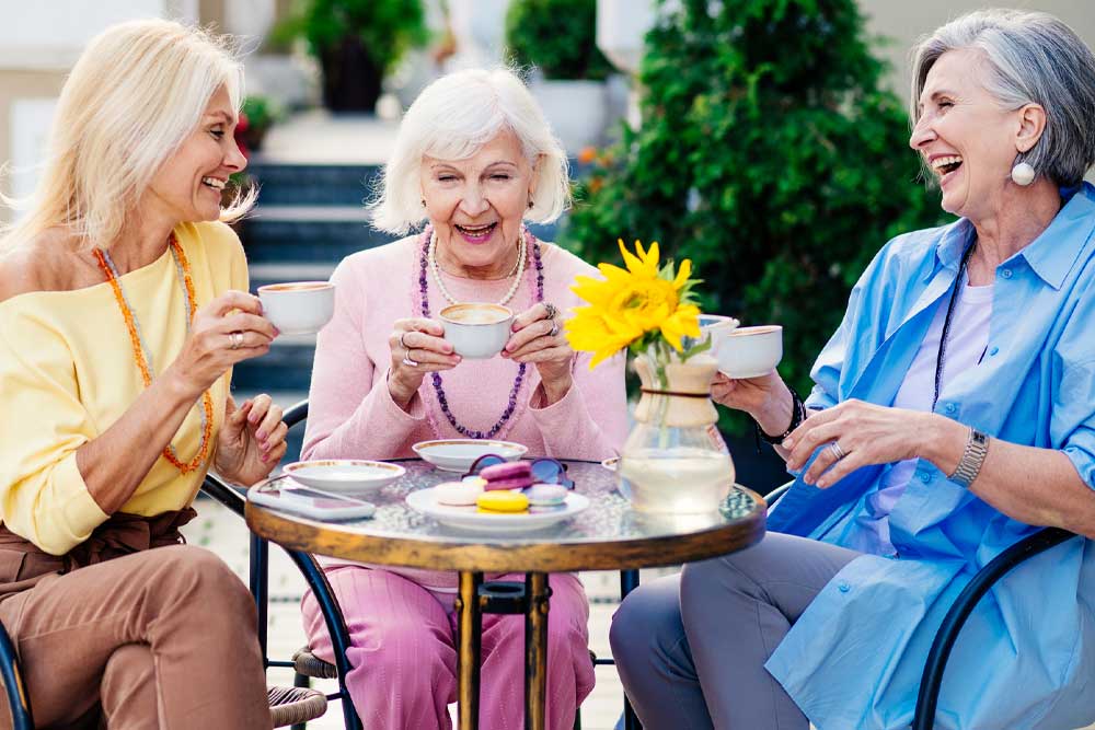 senior women drinking tea together outside